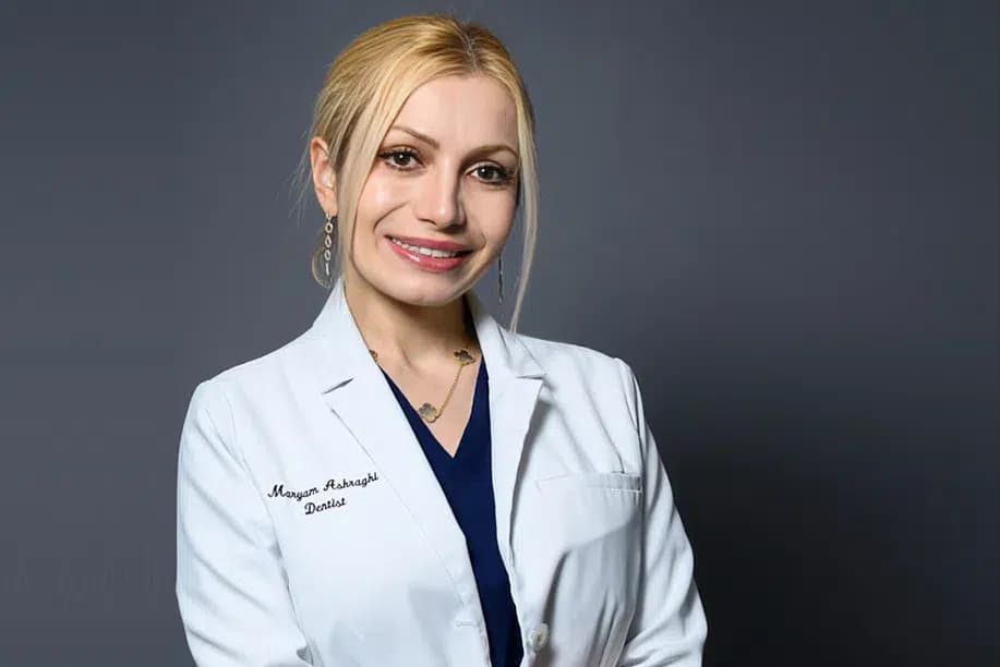 Dr. Maryam Ashraghi smiling in her white coat, dentist and owner of Alpine Dental in Burke, VA