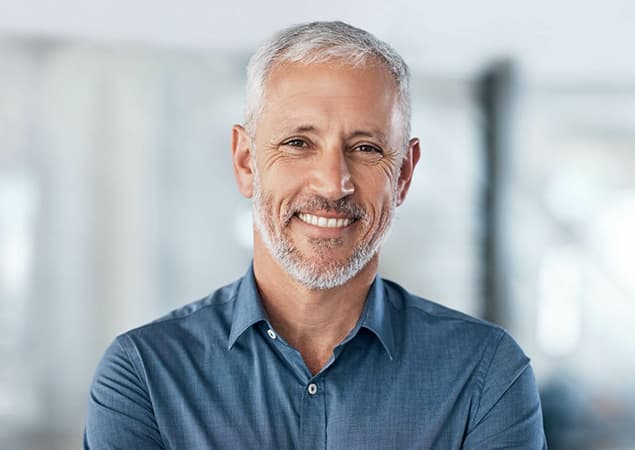 Confident gray-haired man smiling after restorative dentistry with crowns and fillings in Burke, VA