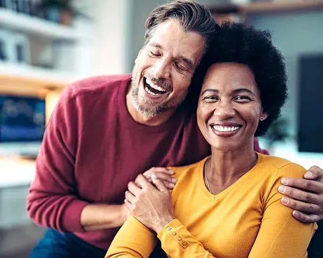 Happy couple laughing together after replacing missing teeth with dental implants in Burke, VA