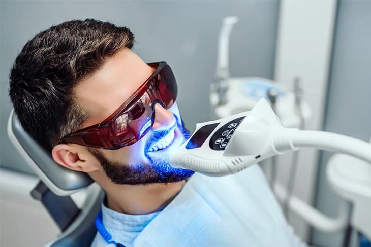 Patient wearing protective glasses during in-office Zoom teeth whitening with a blue light